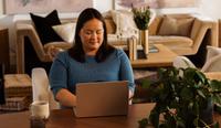 A therapist sits at her desk with her laptop open as she creates her own therapist website, using the top 10 therapist website examples included here.