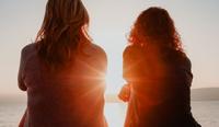 Two female therapists sit together in the sunset and discuss therapist burnout