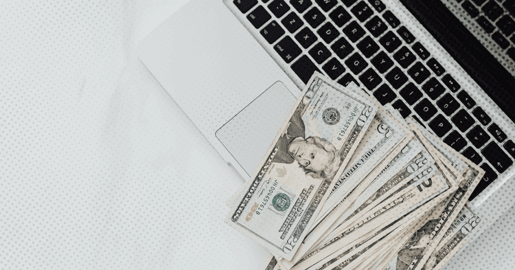 Laptop and money that represents a therapist working on a good faith estimate based on the no surprise act