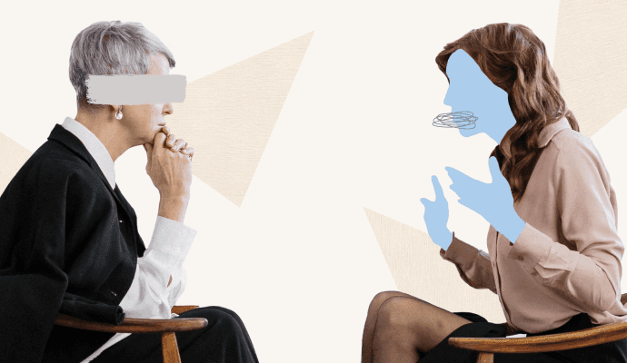 Two women sit facing each other. One has her hand on her chin and is leaning forward, and the other is gesturing.