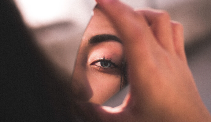 A shard of a mirror reflects the eye of a therapist with imposter syndrome as she ponders how to overcome her imposter syndrome