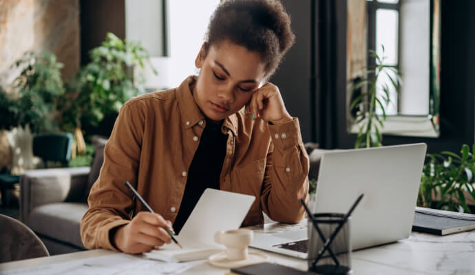 A therapist sits at her cluttered desk, overwhelmed by burnout.