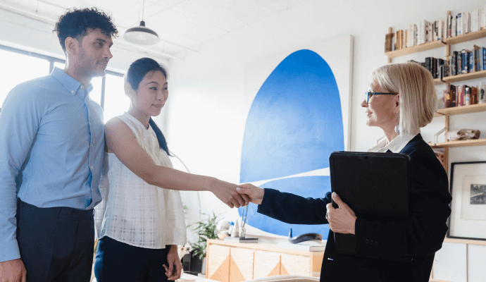 A private practice healthcare entrepreneur shakes hands with two clients.