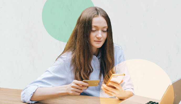 A woman holds her cell phone and a credit card in front of a collage background.