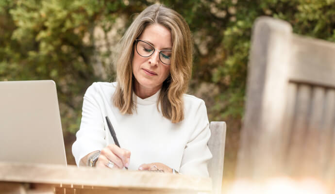 A woman is sitting outside working on a professional will template.