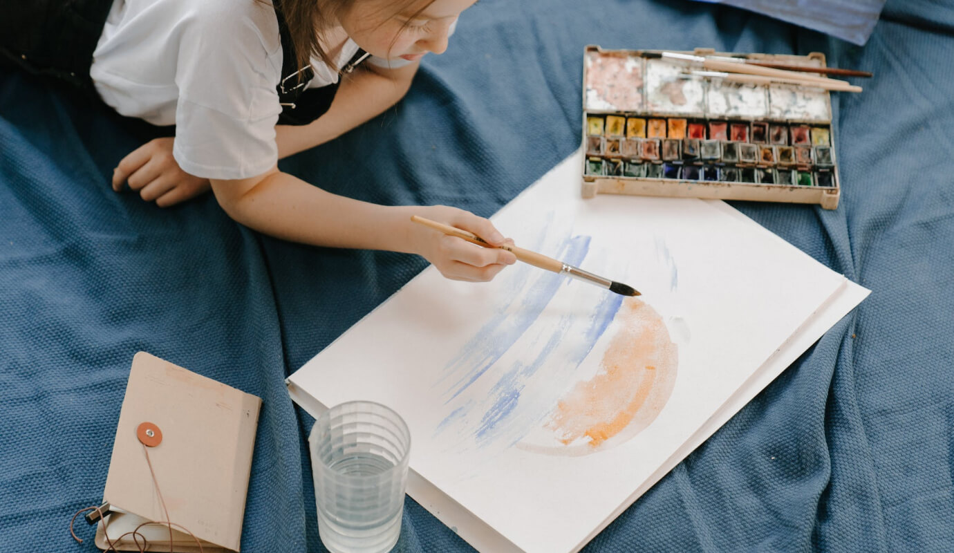 A teen client is painting during therapy, they're present and grounded, showing the benefits of art therapy activities for teenagers.